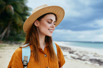 Portrait of smiling young woman wearing hat at beach