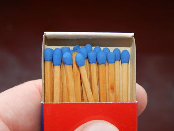 Close-up of hand holding blue colored pencils against white background