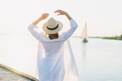 Rear view of woman wearing hat standing against sky