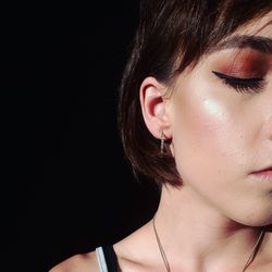 Close-up of young woman with eyes closed against black background