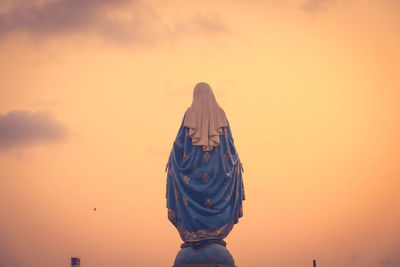 Low angle view of female sculpture against orange sky