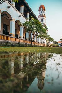 Houses by lake and buildings against sky