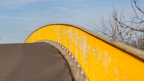 Close-up of yellow metallic structure on land against sky