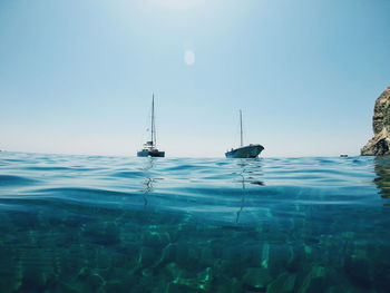 Sailboats in sea against clear blue sky