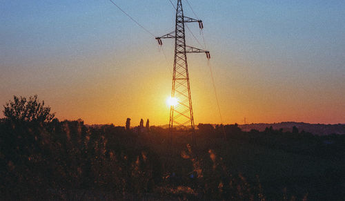 Silhouette electricity pylon on field against sky during sunset