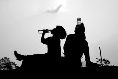 Silhouette people photographing against sky
