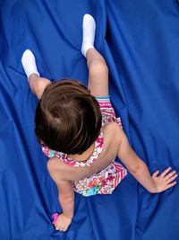 High angle view of girl sitting on blue fabric