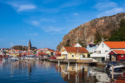 Sailboats moored on river by buildings against sky