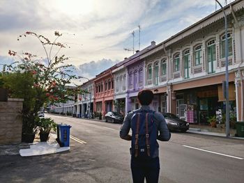 Woman walking on road against cloudy sky