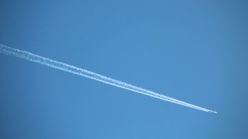 Low angle view of vapor trail against clear blue sky