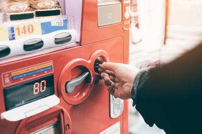 Cropped image of woman inserting coin in vending machine