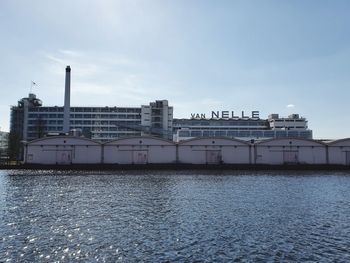 Buildings by river against sky in city