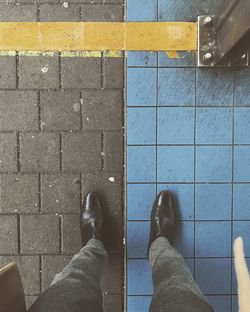 Low section of man standing on tiled floor