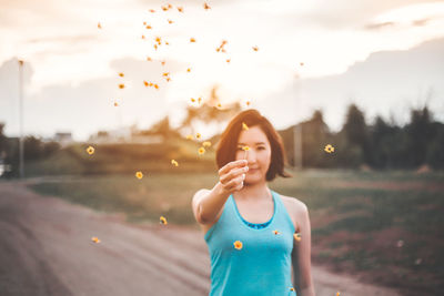 Portrait of woman standing on road against sky during sunset