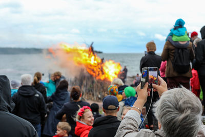 Rear view of people photographing against sky