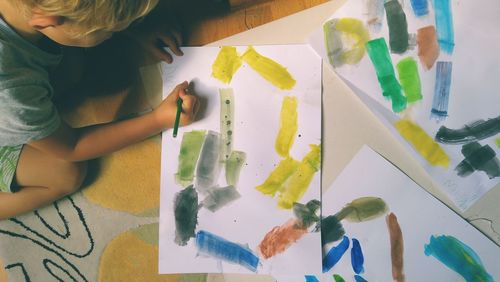 High angle view of boy painting on paper