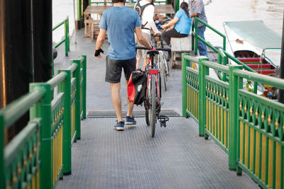 Rear view of man riding bicycle on railing