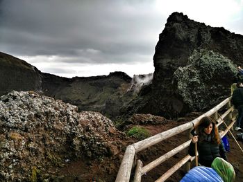 People sitting on rock against sky