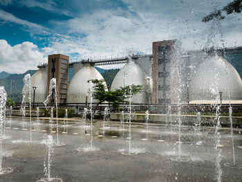 Water fountain against sky during rainy season