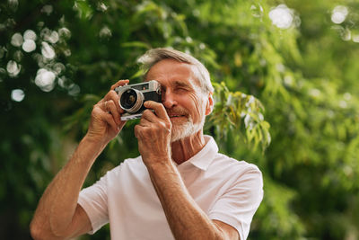 Smiling man holding camera outdoors