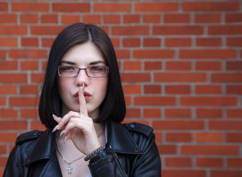 Portrait of young woman against brick wall