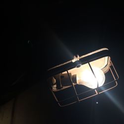 Close-up of illuminated lamp against sky at night