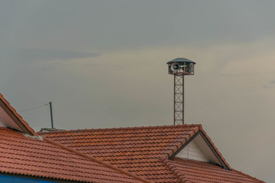 High section of house roof and building against sky