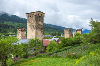 Castle by trees on field against sky