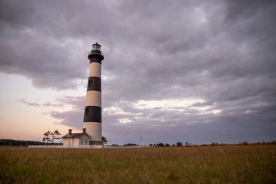 Lighthouse on field against sky during sunset