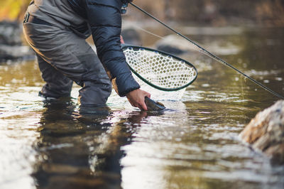 A man releases a trout during a cold morning on a maine river