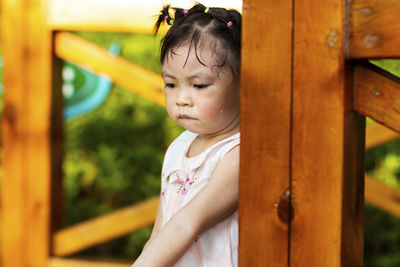 Cute girl looking down while standing by railing