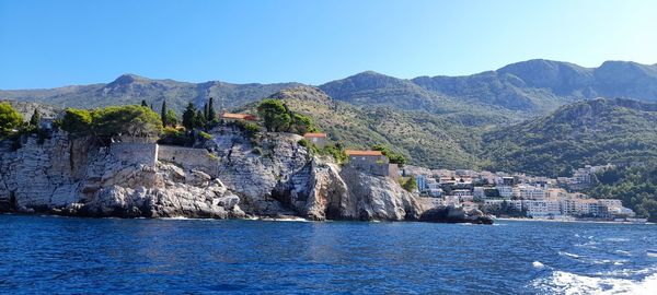 Scenic view of sea and mountains against clear blue sky