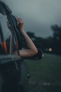 Close-up of hand on car against sky at dusk