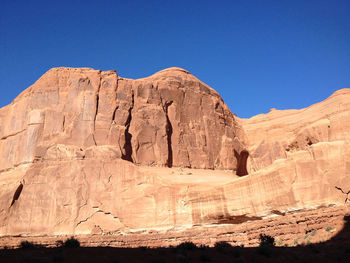 Low angle view of rock formation against clear blue sky