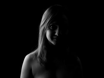 Portrait of young woman against black background