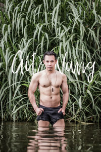 Portrait of young man standing against plants