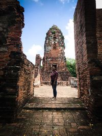 Full length of senior woman amidst buildings against sky