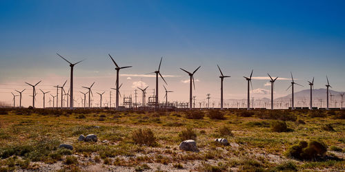 Wind turbines on field against sky