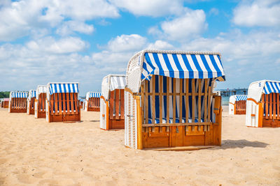 Hooded chairs on beach against sky