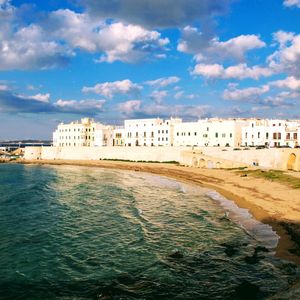 Buildings by sea against blue sky