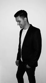 Side view of young man looking away against white background