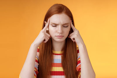 Portrait of a beautiful young woman against yellow background