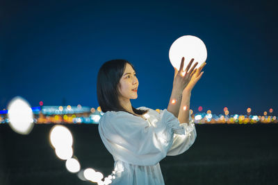 Digital composite image of woman standing against illuminated sky