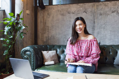 Young woman sitting on sofa at home