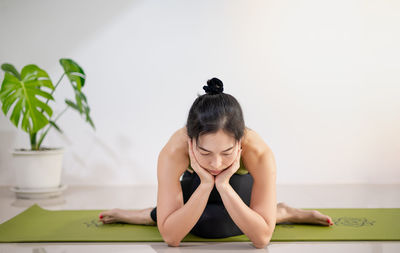 Woman doing yoga on the green yoga mat for meditite and excercise in the home.