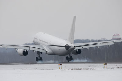 Airplane landing on runway with smoke from chassis in winter time. touchdown with landing gear smoke