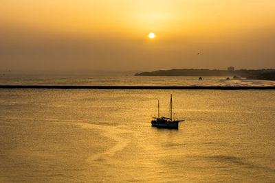 Boat sailing on sea against sky during sunset