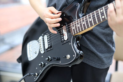 Midsection of man playing guitar