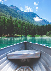 Boat moving on lake by mountains against sky