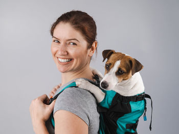 Portrait of young woman with dog against white background